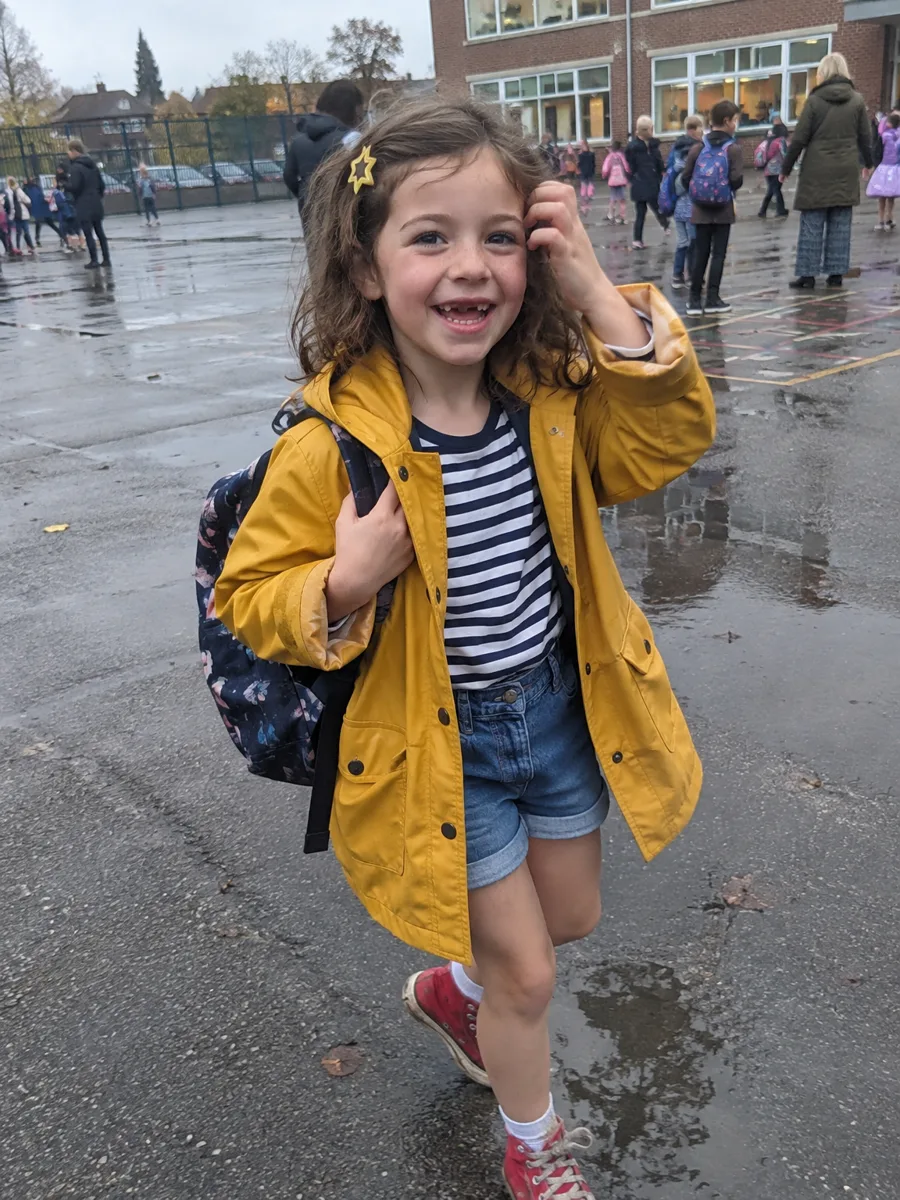 Mia, a real 6-year-old girl in a yellow raincoat in the school playground